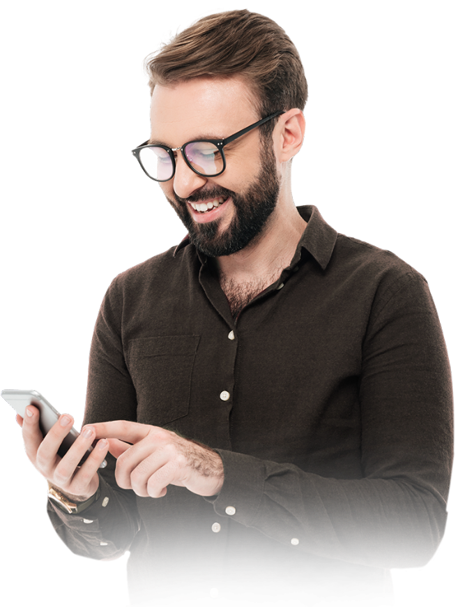 Homem sorridente com barba e óculos, vestindo uma camisa marrom e usando um smartphone.